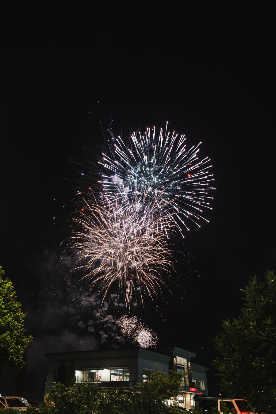Fireworks bursting over a lit storefront at night